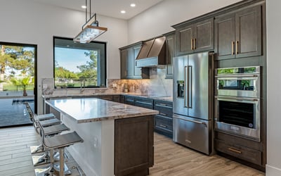 A luxury Scottsdale kitchen with stainless appliances, large island, and elegant marble counters overlooks the pool and golf course.