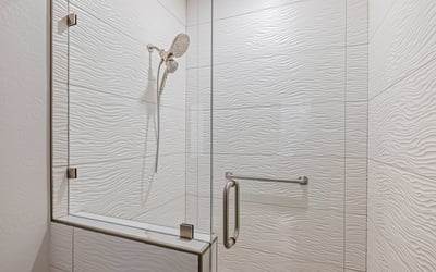 A frameless glass shower with textured wall tile and updated fixtures highlights the hall bath s modern upgrades.