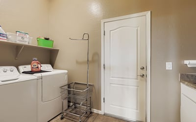Laundry room with washer/dryer setup, utility sink, and storage shelving makes daily chores efficient and organized.