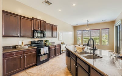 Bright windows frame backyard views from the gourmet kitchen, complete with granite counters, sleek appliances, and warm cabinetry.