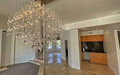 Dazzling chandelier paired with a sleek built-in wet bar creates a striking entry focal point modern elegance meets everyday function.