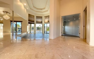 Elegant entryway featuring high ceilings, marble floors, and crystal chandelier lighting that leads into the bright open living space.