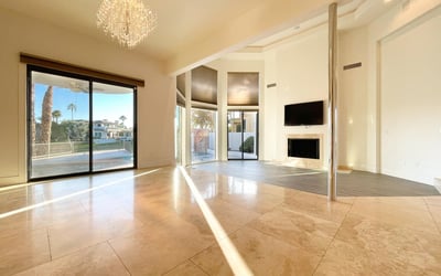 Beautifully designed living room with abundant sunlight, crystal chandelier, and sliding glass doors leading to the lakefront patio.