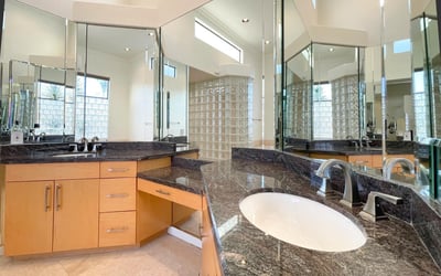 Modern bath design with granite countertops, high-end fixtures, and surrounding mirrors that amplify light and sophistication.