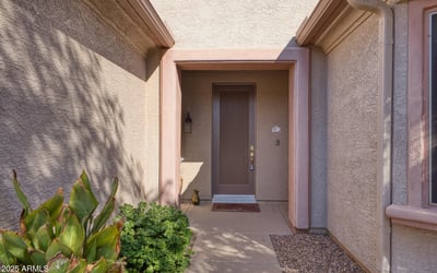 A covered entry framed by natural desert tones offers a warm welcome. Thoughtfully designed for shade and comfort, this entrance sets the tone for a peaceful home experience.