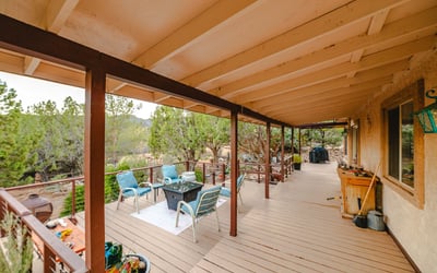 This deck's outdoor lounge area offers a welcoming place to gather, relax, and enjoy views of desert terrain and rolling hills in the distance.