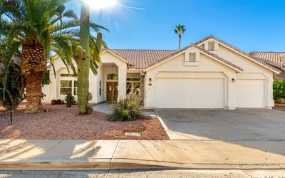 Attractive Scottsdale home exterior surrounded by mature palm trees and native desert landscaping. The well-maintained fa ade, tile roof, and inviting front walkway highlight the home's updated design and strong curb appeal.