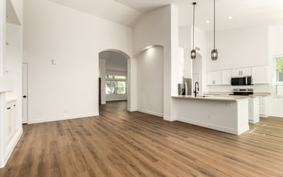 Expansive Scottsdale interior showing the open connection between living room and kitchen. High ceilings, recessed lighting, and updated finishes enhance the home's modern open floor plan.