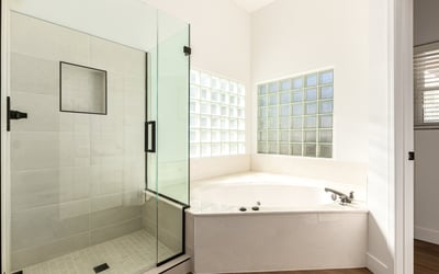 Relaxing Scottsdale bathroom featuring a glass walk-in shower and large soaking tub surrounded by natural light from glass block windows. Modern finishes create a luxurious atmosphere.