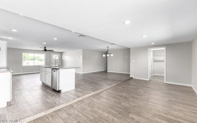 Wide-open living and dining area with wood-look tile flooring and recessed lighting, leading toward the backyard great for entertaining in this Phoenix home for sale.