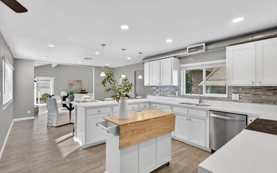 Stylish kitchen with updated white cabinetry, sleek counters, stainless appliances, and open sightlines to main living areas.