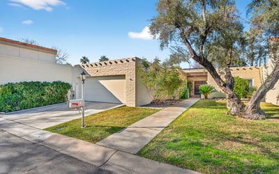 Clean, well-kept front exterior with attached garage, private walk-up entry, and manicured landscaping inside a secure Phoenix community.
