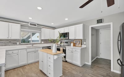 Updated kitchen showcasing white cabinetry, contemporary backsplash, stainless appliances, and abundant counter space.