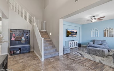 Welcoming entry foyer with soaring ceilings, tile flooring, and staircase leading to the loft and upper living areas of this spacious Queen Creek home.
