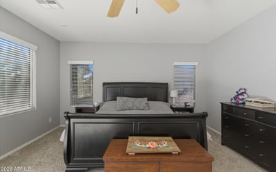 Bright primary bedroom with neutral finishes, ceiling fan, and expansive floor space offering comfort and versatility within the home s upper level.