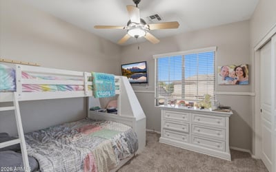 Cozy secondary bedroom with bunk bed arrangement, neutral paint, and large window allowing natural light into the room.