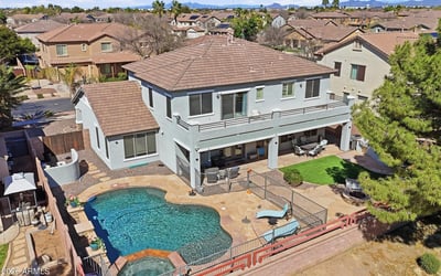 Drone perspective highlighting the backyard retreat with pool, spa, covered patio seating, and landscaped outdoor entertaining areas.