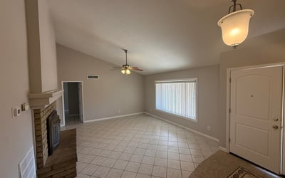 Interior perspective showing the open living space flowing toward the front entry. Neutral paint and tile flooring enhance the clean and inviting feel of this Glendale home.