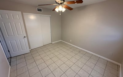 Bright bedroom with tile flooring and ceiling fan light fixture. The simple layout provides flexibility for furniture arrangement and everyday comfort.