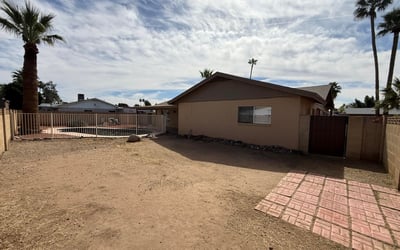 Rear exterior view highlighting the covered patio, fenced pool, and spacious yard. The layout provides a welcoming outdoor setting ideal for relaxing evenings and weekend gatherings.
