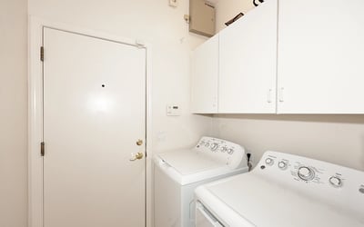 Functional laundry room with washer, dryer, and built-in cabinets. This Phoenix home adds convenience with dedicated utility space.