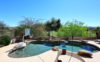 Resort-style pool area with rock features and panoramic golf course views. This Phoenix property delivers a peaceful outdoor setting perfect for enjoying Arizona living.