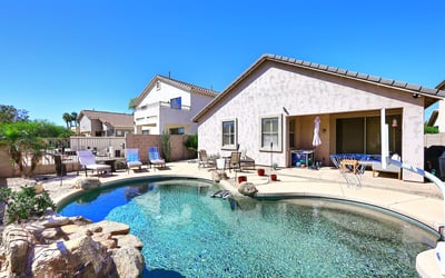 Backyard with Pebble Tec pool, rock waterfall feature, and spacious patio. This Phoenix home highlights outdoor living with low-maintenance desert landscaping.