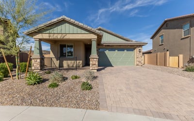 Stunning Peoria home exterior with paver driveway, stone detailing, and desert landscaping. Offers low-maintenance living and strong curb appeal.