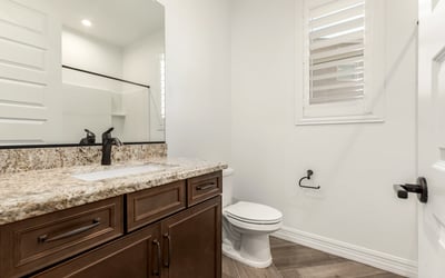 Guest bathroom featuring granite counters, wood cabinetry, and modern fixtures, blending style and everyday functionality.