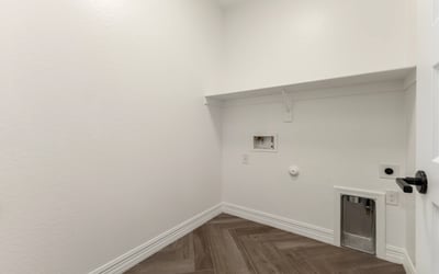 Dedicated laundry area with storage shelving and utility hookups, designed for efficient household tasks.