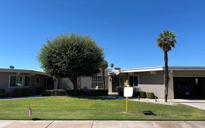 Attractive Sun City exterior featuring green lawn, shade trees, and inviting curb appeal that enhances the home's overall charm.