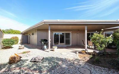 Private backyard with covered patio, desert landscaping, and outdoor seating areas ideal for relaxing or entertaining in Sun City.