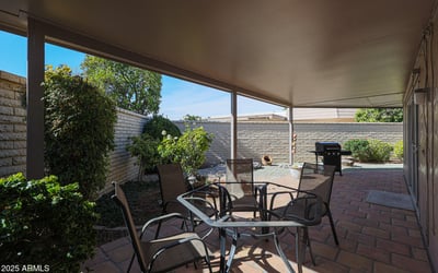 Private covered patio with mature landscaping and seating space, perfect for relaxing or hosting guests outdoors.