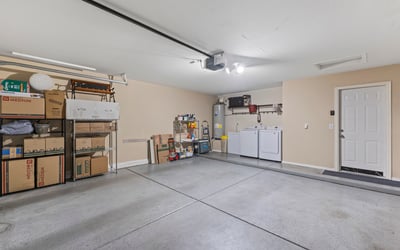 Spacious garage with shelving, laundry setup, and room for storage and vehicles, offering convenience and organization.