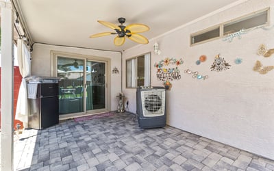 Covered patio space with pavers and ceiling fan, perfect for relaxing outdoors or hosting guests in a comfortable setting