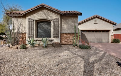 Attractive Phoenix home with desert landscaping, stucco exterior, and stone details, offering low-maintenance curb appeal and a welcoming entrance.