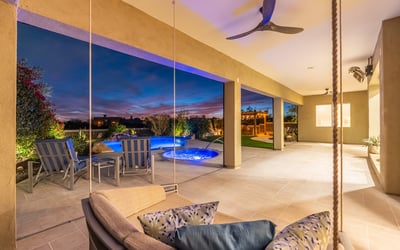 Covered patio with a modern swing seat overlooking the pool and spa, creating a unique Scottsdale outdoor living experience at night.