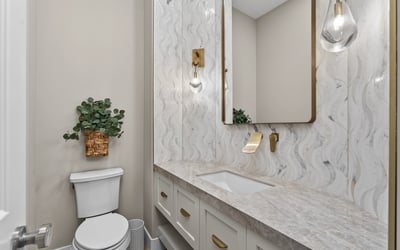 Elegant powder room with updated vanity, quartz countertop, decorative backsplash, and modern lighting in this Scottsdale residence.