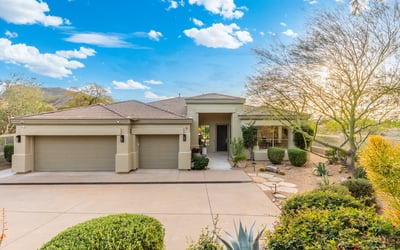 Scottsdale home exterior featuring desert landscaping, three-car garage, and welcoming entry for strong curb appeal.
