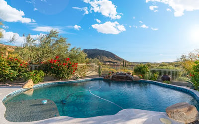 Scottsdale pool with rock waterfall feature, desert landscaping, and mountain views, offering a serene and private outdoor setting.