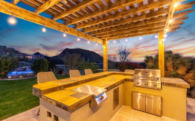 Scottsdale outdoor kitchen with built-in grill, seating area, and scenic mountain backdrop, designed for hosting gatherings.