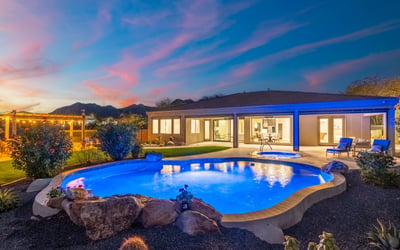 Scottsdale backyard featuring pool, spa, pergola kitchen, and desert landscaping under a dramatic sunset sky.
