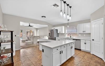 Spacious kitchen with large island, white cabinetry, and ample prep space. Open layout flows into living areas, making it ideal for gatherings in this Casa Grande property.