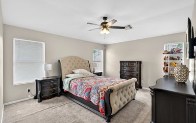 Generous primary bedroom with ceiling fan, soft carpet, and multiple windows. A relaxing retreat designed for comfort in this Casa Grande home.