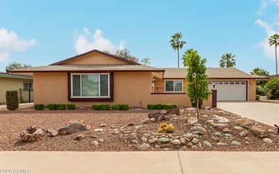 Front exterior with classic desert landscaping and mature greenery. This Sun City property highlights low-maintenance design and updated home features.