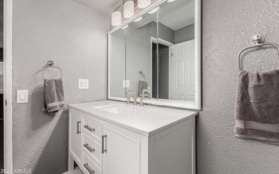Well-lit vanity area with updated cabinetry and modern mirror. This Sun City home features upgraded bathrooms and functional design.
