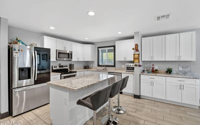 Renovated kitchen featuring granite countertops, stainless appliances, and a large island, designed for both everyday use and entertaining.