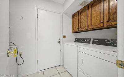 Complete with upper storage cabinets and included laundry appliances, this dedicated laundry room offers efficiency and convenience. The practical layout helps maximize organization and household functionality.