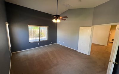 Large primary suite offering soaring ceilings, plush carpeting, and ample space for a full bedroom set. Multiple windows provide natural light and enhance the welcoming atmosphere.