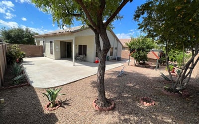 Inviting backyard with mature trees, desert landscaping, and a spacious covered patio. The thoughtfully designed outdoor space provides shade, privacy, and plenty of room for gatherings, recreation, or peaceful relaxation.